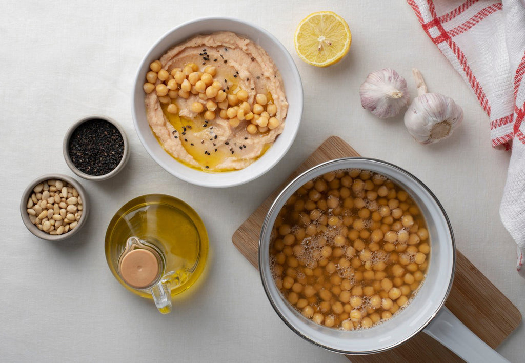 Legumbres en conserva cocinadas. Plato y cazuela de garbanzos cocidos. Hummus. Aceite de oliven virgen extra (A.O.V.E), ajos y semillas